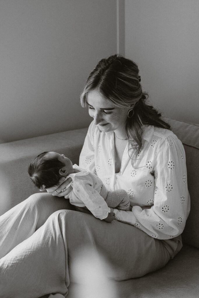 Moeder zit op bank en kijkt naar newborn baby