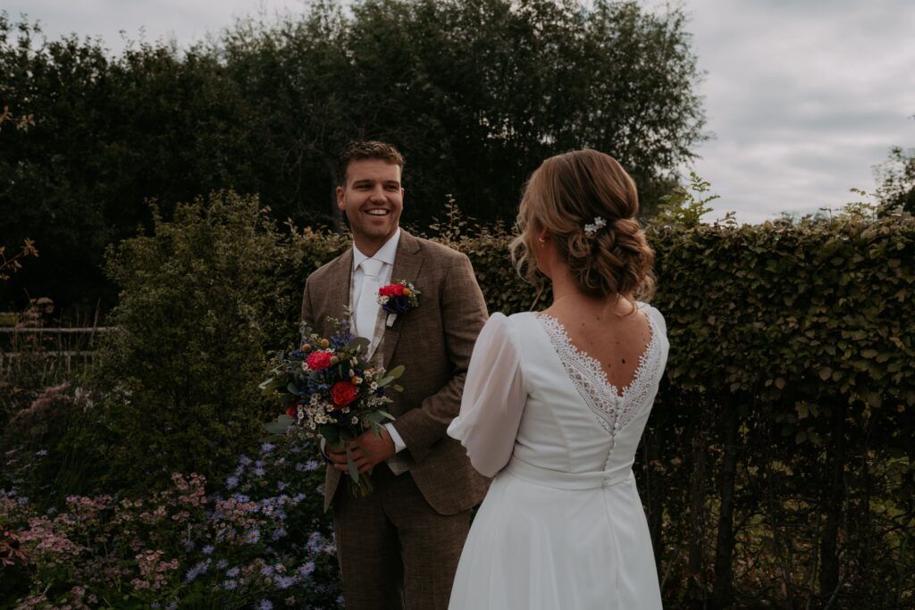 Bruidegom en bruid bij de first look. bruidegom draait om naar bruid en lacht