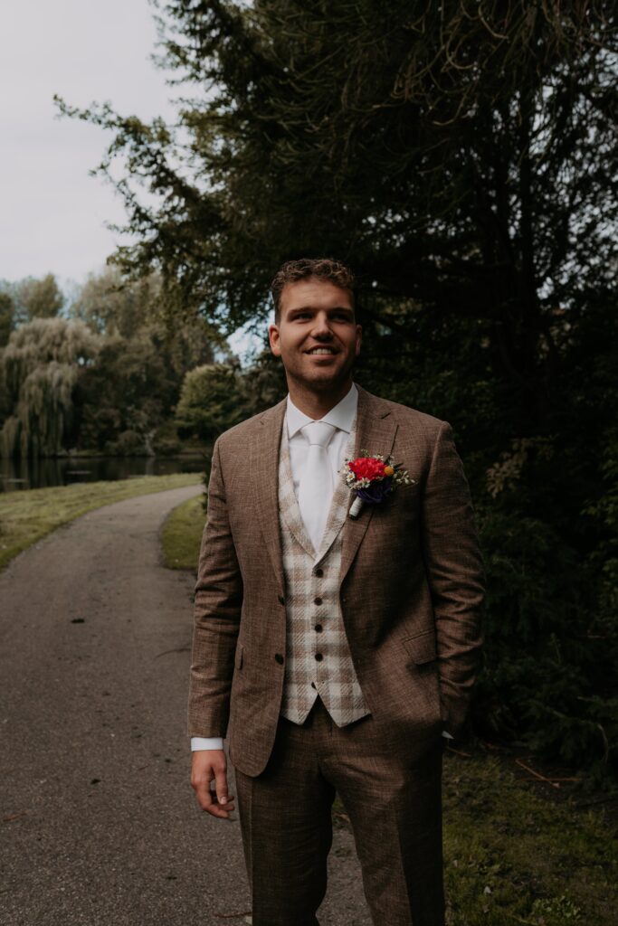 Bruidegom in pak lacht met hand in zak