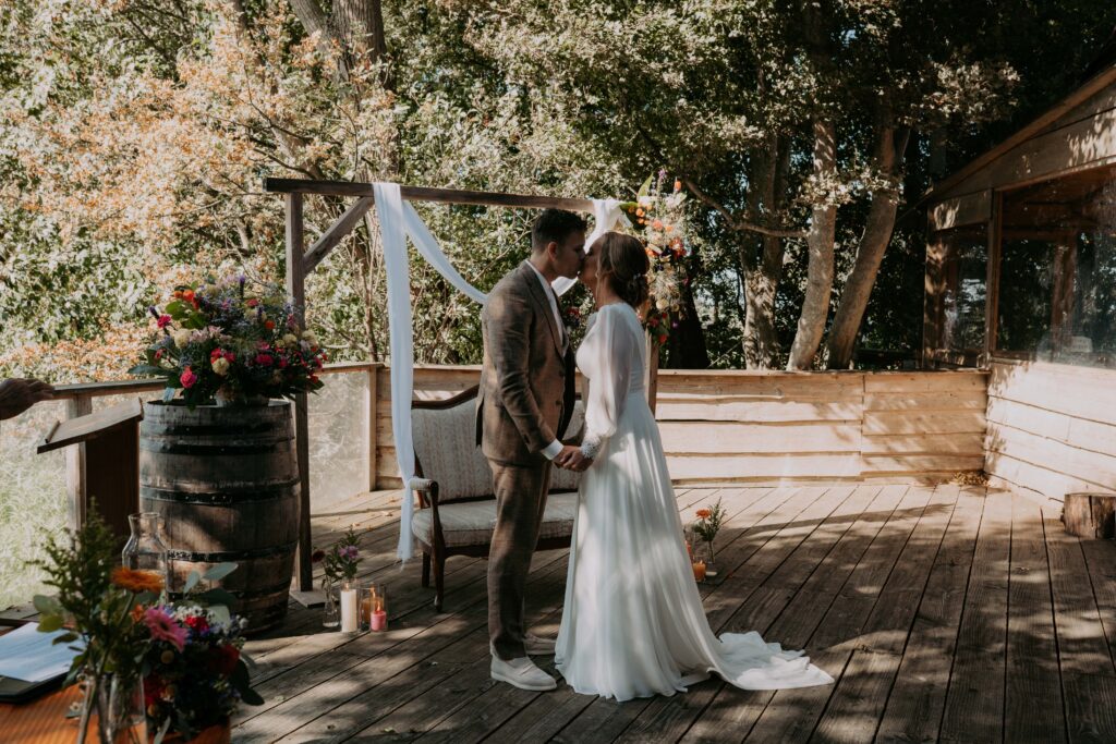 Bruidspaar geeft elkaar de kus en houdt handen vast