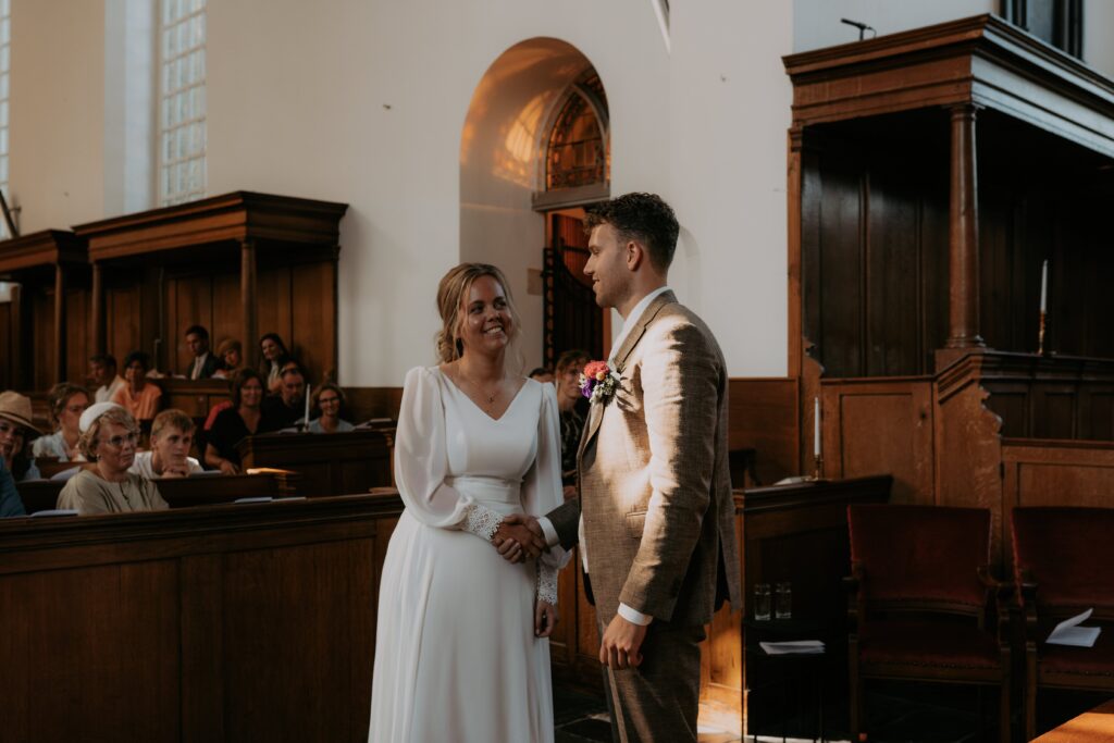 Bruidspaar geeft elkaar de rechterhand in kerk