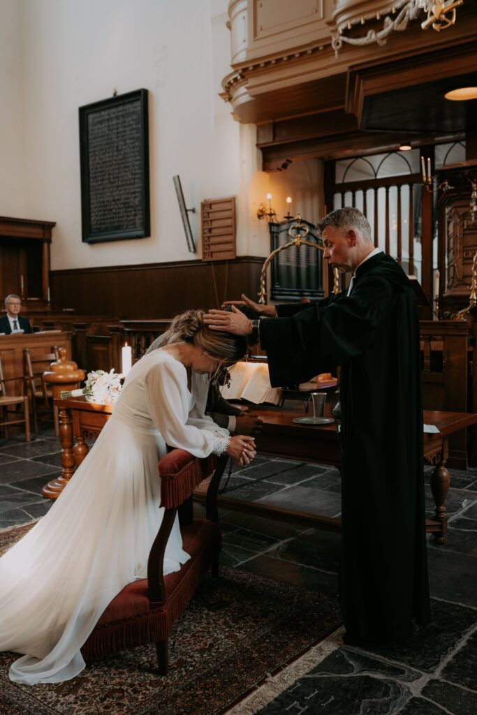 Bruidspaar in de kerk op knielbank, gezegend door de dominee