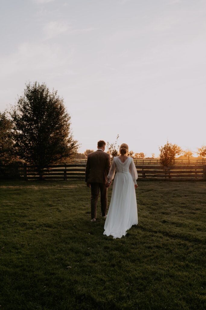 Bruidspaar loopt in weiland tijdens golden hour