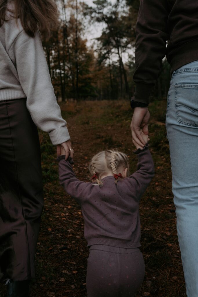 meisje houdt handen van papa en mama vast