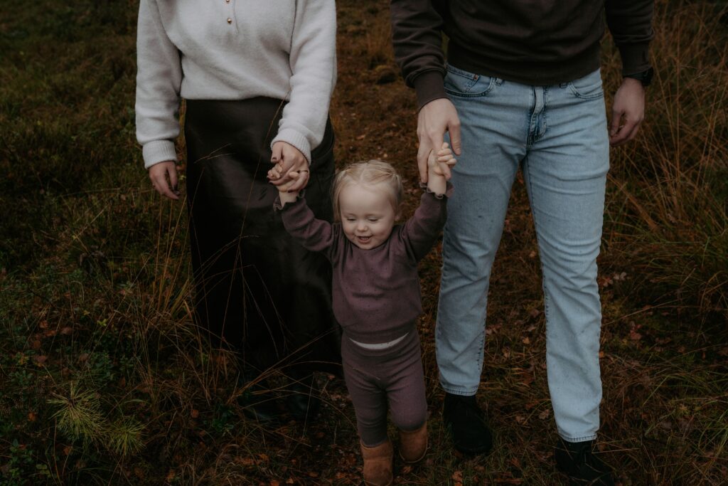 meisje houdt handen van papa en mama vast