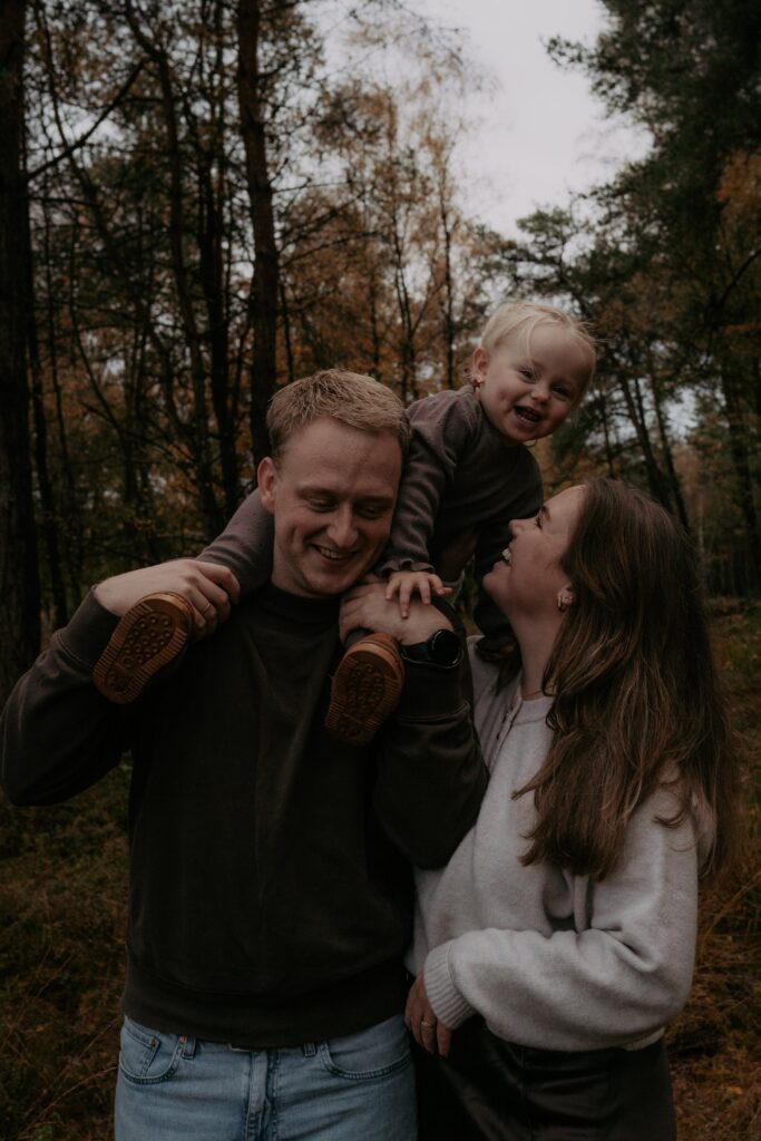 gezin in bos in Ede, meisje op schouders papa en lacht