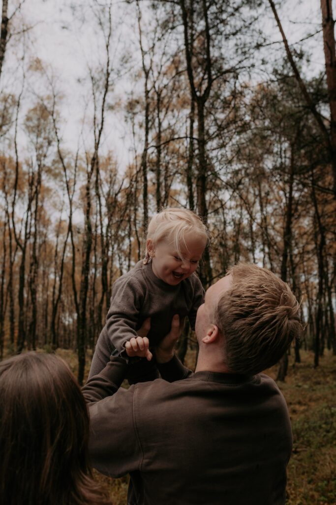 vader houdt dochter vast in de lucht in bos in Ede