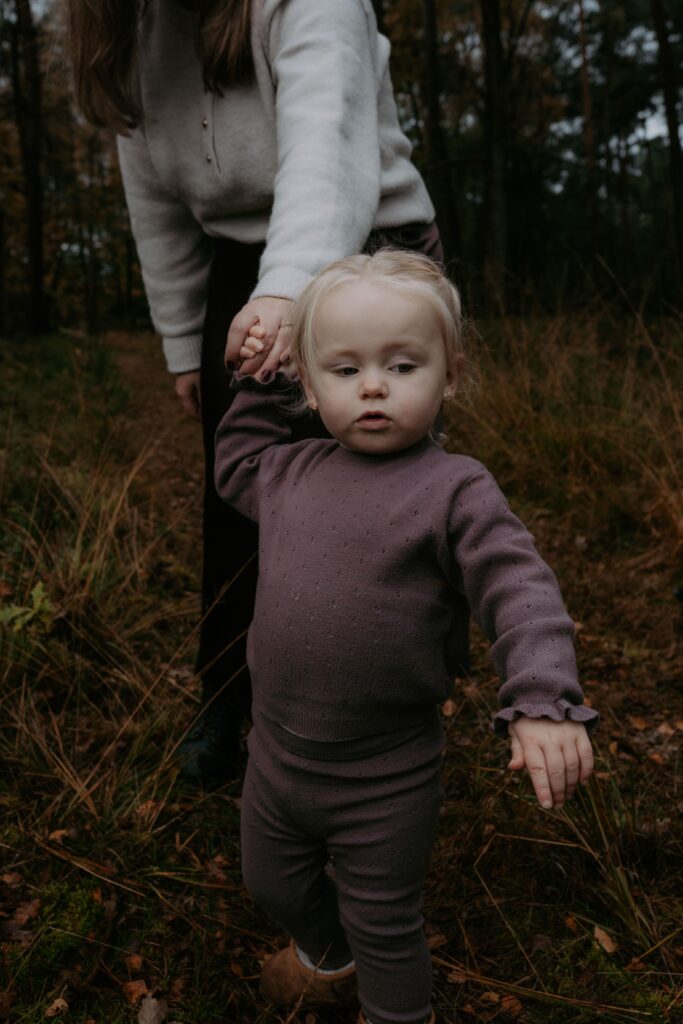dochter houdt moeder haar hand vast in bos in Ede en loopt in bos
