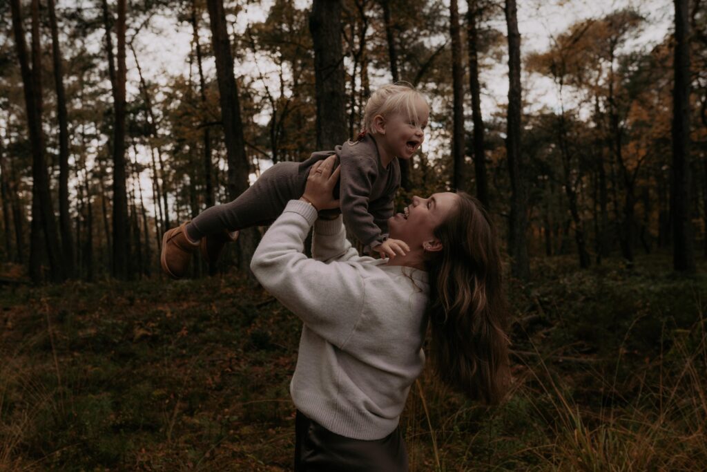 Moeder met dochter in bos in Ede, moeder houdt dochter in de lucht