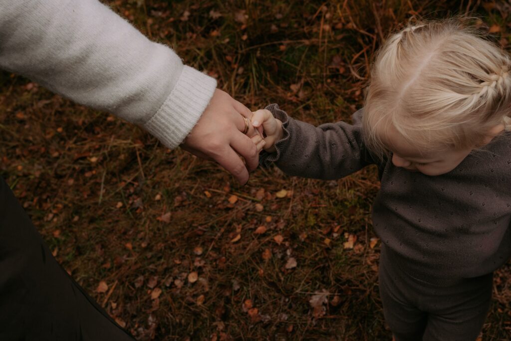 dochter houdt moeder haar hand vast in bos in Ede