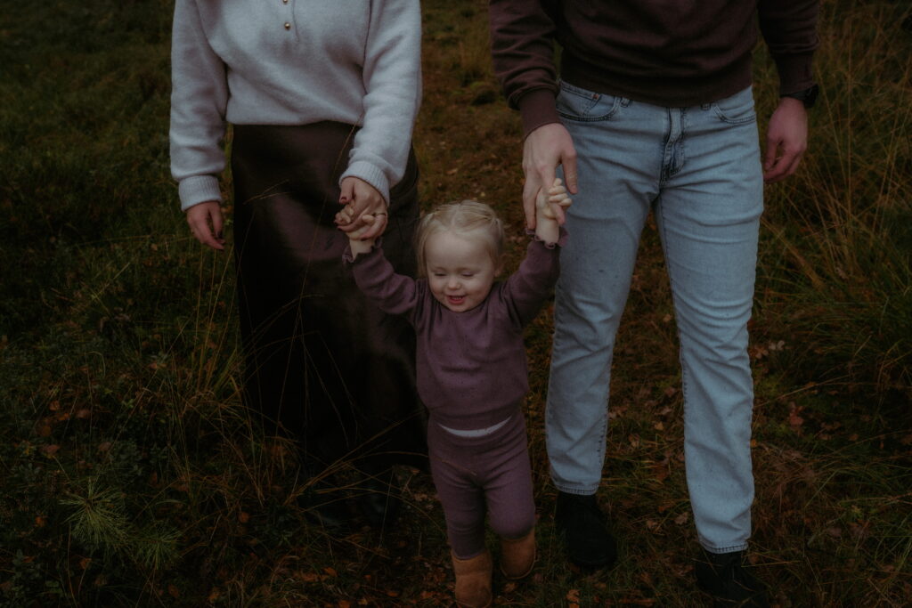 meisje houdt handen van papa en mama vast in bos in Ede
