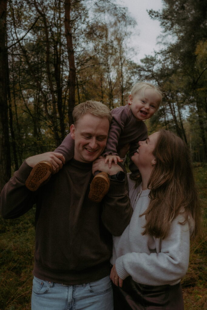gezin in bos in Ede, meisje op schouders papa en lacht