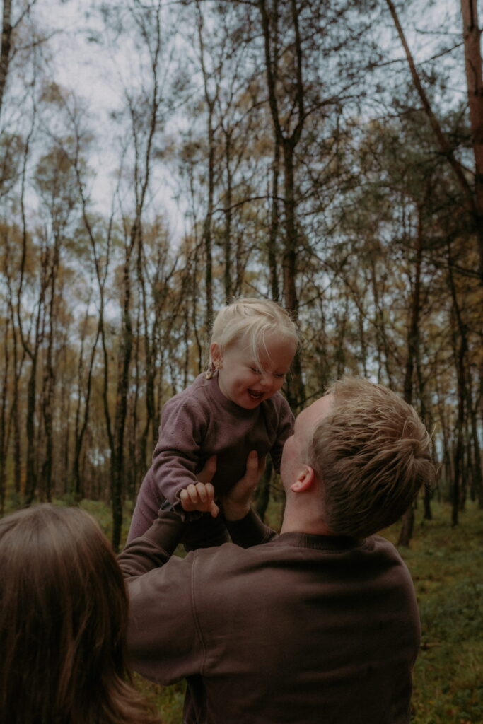 vader houdt dochter vast in de lucht in bos in Ede