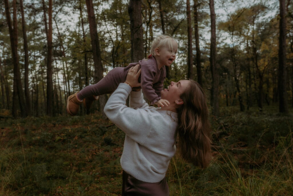 Moeder met dochter in bos in Ede, moeder houdt dochter in de lucht