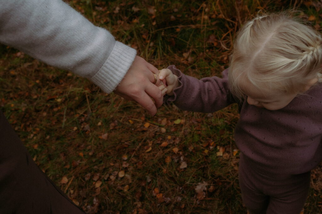 dochter houdt moeder haar hand vast in bos in Ede
