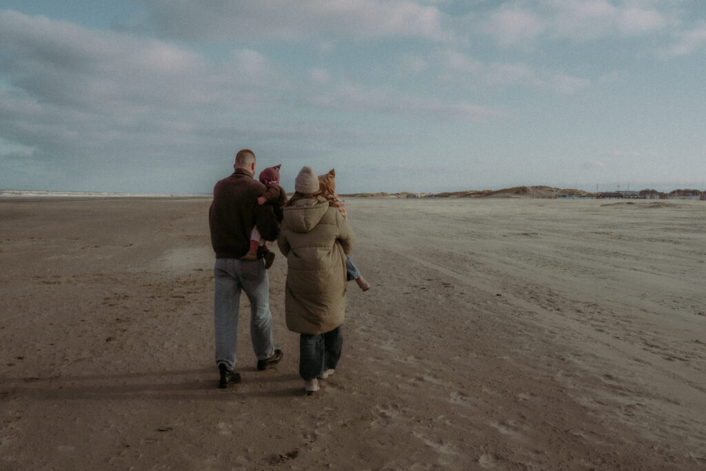Gezin met vader en moeder en twee dochters lopen over het strand