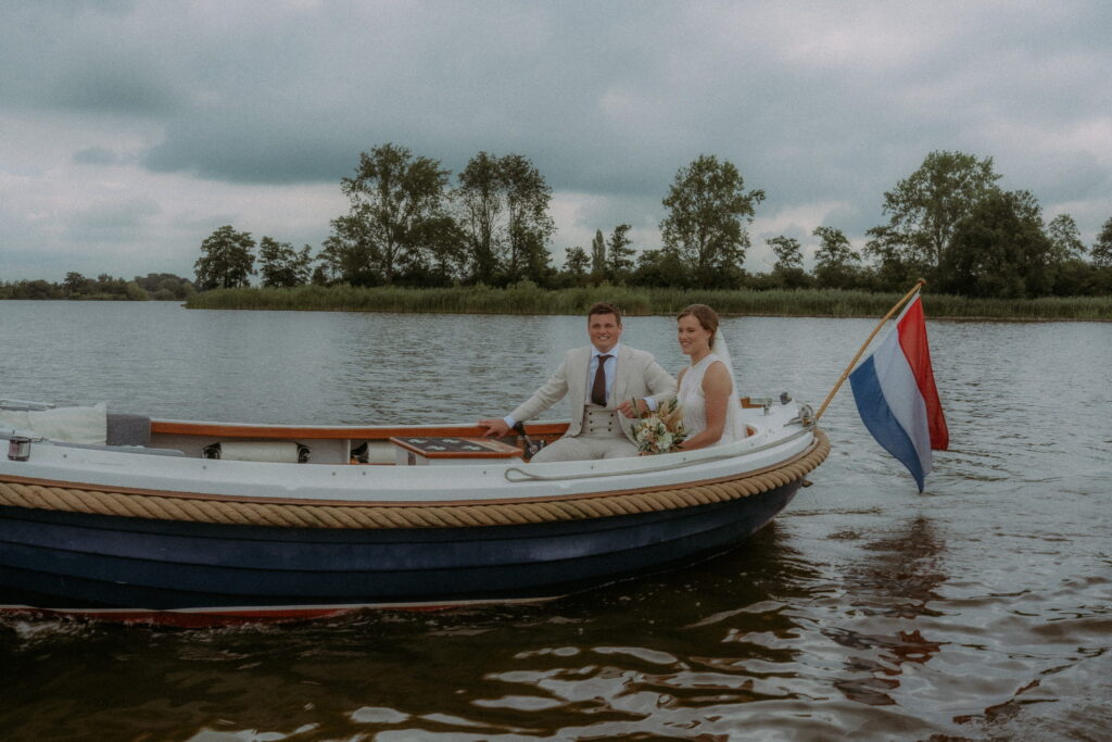 Bruidspaar in een bootje op het water met nederlandse vlag