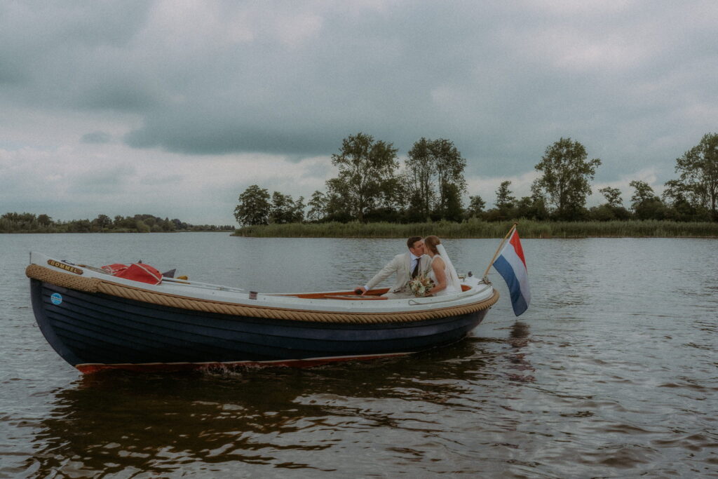 Bruidspaar in bootje op het water geven elkaar een kus