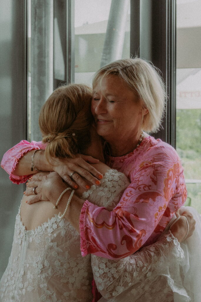 bruid geeft knuffel aan vrouw met roze jurk