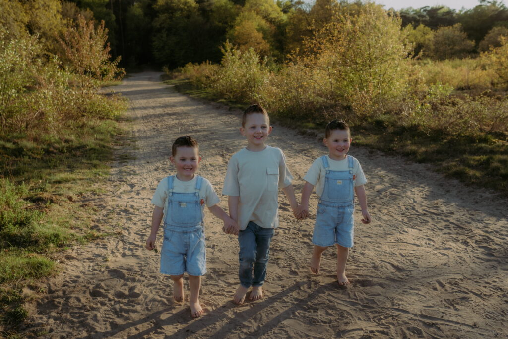 drie jongetjes lopen hand in hand over de hei in Ede